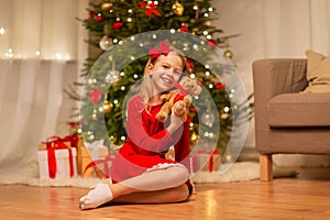 Girl in red dress hugging teddy bear at home