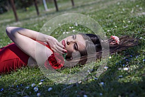 Girl with red dress lying on spring meadow