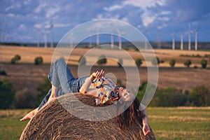 Girl in a red dress near a round bale of straw