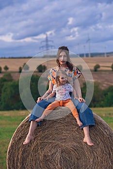 Girl in a red dress near a round bale of straw