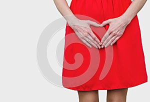 Girl in the red dress pressed her hands to the stomach, heart gesture, love. Women`s health, sexuality