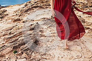 Girl in red dress among rocks and cliffs along the Coast of Algarve