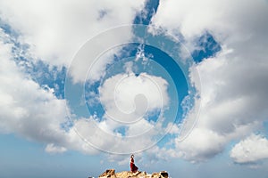 Girl in red dress among rocks and cliffs along the Coast of Algarve