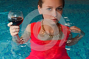 Girl in red dress standing with glass of wine in