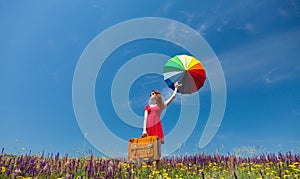 Girl in red dress with umbrella and suitcase