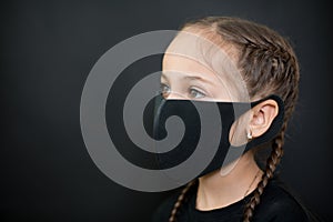 Girl with red eyes and black a medical mask on a black background, copy space. Concept of people who are isolated in a coronavirus