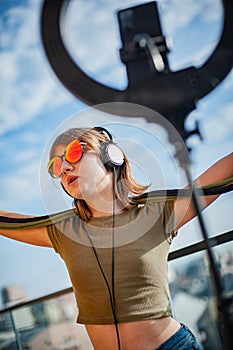 Girl with red glasses dances on balcony and broadcasts live