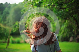 Girl with red hair blowing in the wind breathing deeply and looking away  with a blurred nature background. Soft focused