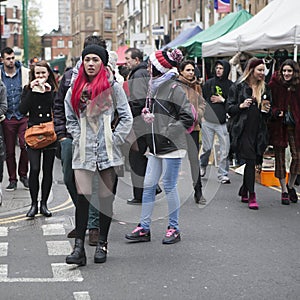 Girl in red hair dressed in cool Londoner style walking in Brick lane, a street popular among young trendy people