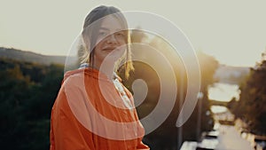 The girl with red hair and freckles, sitting at the entrance to the park, looks directly in front of the camera. Dressed