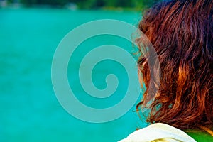 Girl with red hair at lake. Blur background.