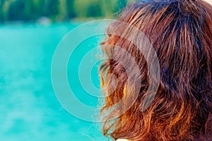 Girl with red hair at lake. Blur background.
