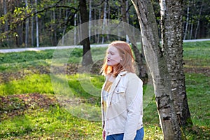 Girl with red hair in the park in autumn season, sunny day