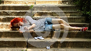 The girl with red hair sitting on the stairs. Cheat sheet . Crib sheet . Crumpled paper.