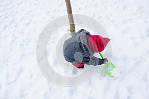 Girl with red hat shovel dig snow