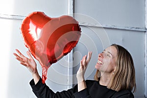 a girl with red heart-shaped balloons smiles and enjoys life. Caucasian woman celebrating valentine& x27;s day. A note to