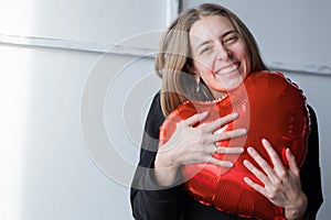 a girl with red heart-shaped balloons smiles and enjoys life. Caucasian woman celebrating valentine& x27;s day. A note to