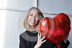 a girl with red heart-shaped balloons smiles and enjoys life. Caucasian woman celebrating valentine& x27;s day. A note to