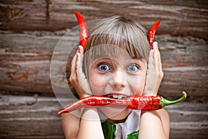 Girl with a red hot chili pepper in her mouth show devil horns