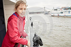 Girl in red jacket at railing on pleasure boat photo