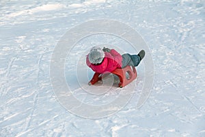 Girl in a red jacket rides off a snow slide