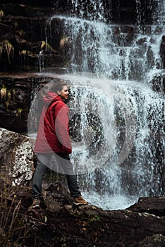 Girl in red jacket by the waterfall