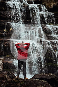 Girl in red jacket by the waterfall