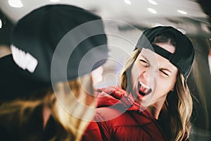 Girl in red jacket wearing stylish cap grimacing at false glass
