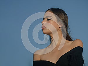 Girl with red lips on blue sky background. Beauty and fashion, cosmetics. Fashion look of stylish woman in black, makeup