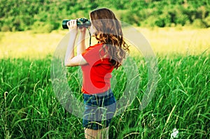 Girl in a red looking through binoculars. woman looking through