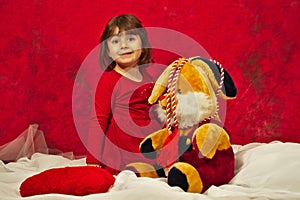 A girl in red playing with the stuffed bunny toy