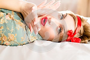 Girl with red ribbon on head & red lips lying on bed