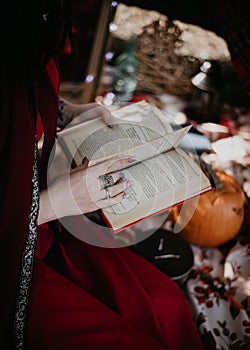 a girl in a red robe reads a witchcraft book