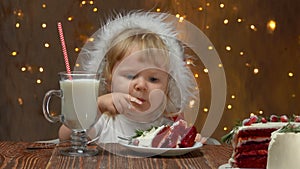 Girl in red Santa Claus Hat is eating red velvet cake and drinking milk