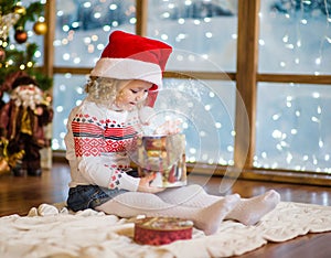 Girl in red santa hat opening gifts at Christmas