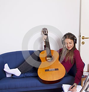 A girl in a red shirt .Holds a guitar and listens to music.