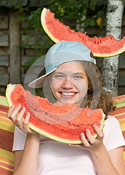 Girl with a red slice of watermelon in hands and on her head photo