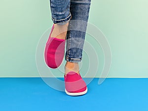 Girl in red sneakers and ripped jeans walking on the blue floor.