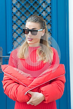 Girl in red sweater, coat on blue door in paris