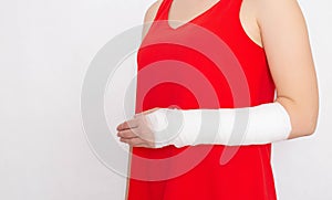 Girl in a red T-shirt with a broken arm in a tight bandage and plaster on a white background. Radial Fracture Treatment Concept,