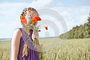 Girl with red tulip flowers posing in the wheat field, bright sun, beautiful summer landscape