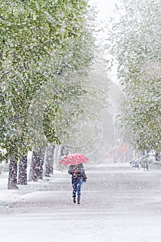 Girl with red umbrella in Snow Storm in April.