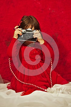 A girl in red using a vintage photo camera