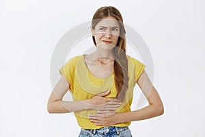 Girl regret eating food near subway. Portrait of displeased worried woman feeling discomfort in stomach holding hands on