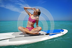 Girl relaxed sitting on paddle surf board SUP