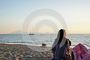 Girl relaxes on the beach, watching the sunset.