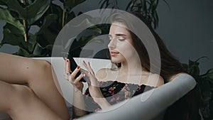 The girl relaxes in the warm milk tub and uses her mobile phone. A beautiful young girl uses a phone while sitting and