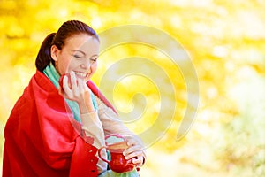 Girl relaxing in the autumn park enjoying hot drink