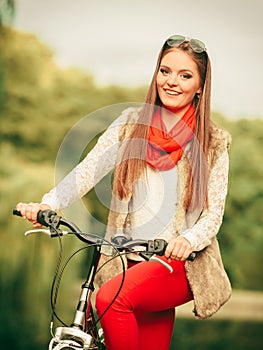 Girl relaxing in autumnal park with bicycle.