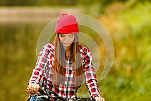 Girl relaxing in autumnal park with bicycle.